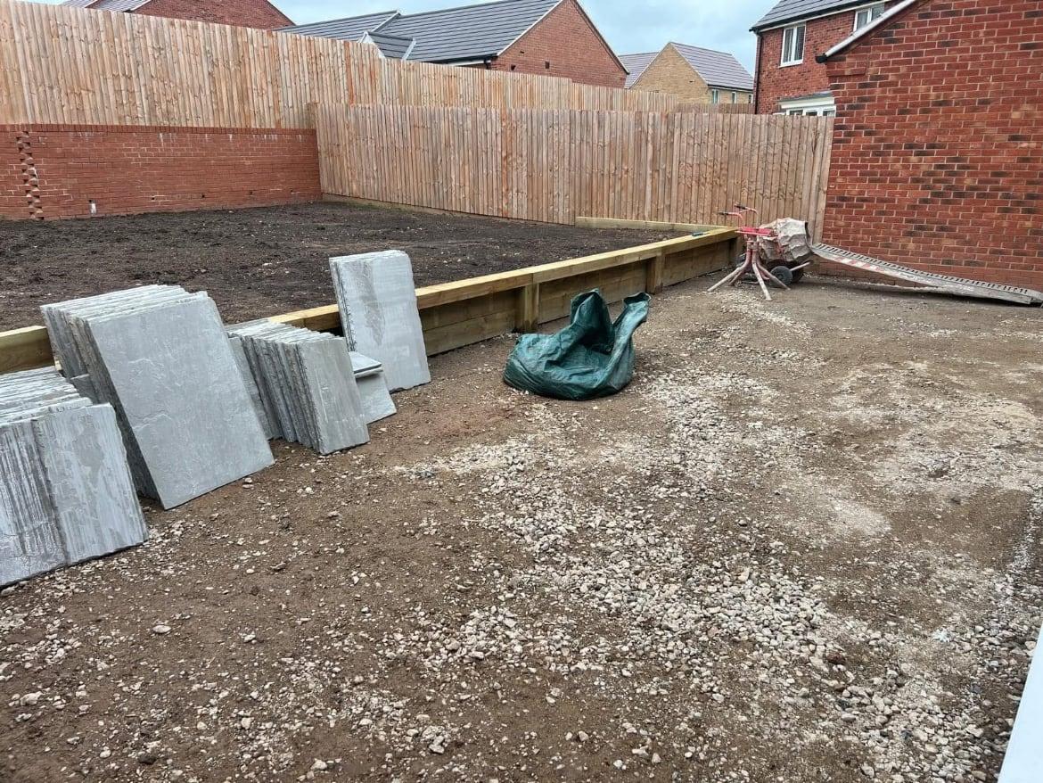 Bare new-build garden with sleepers and paving slabs delivered ready for work