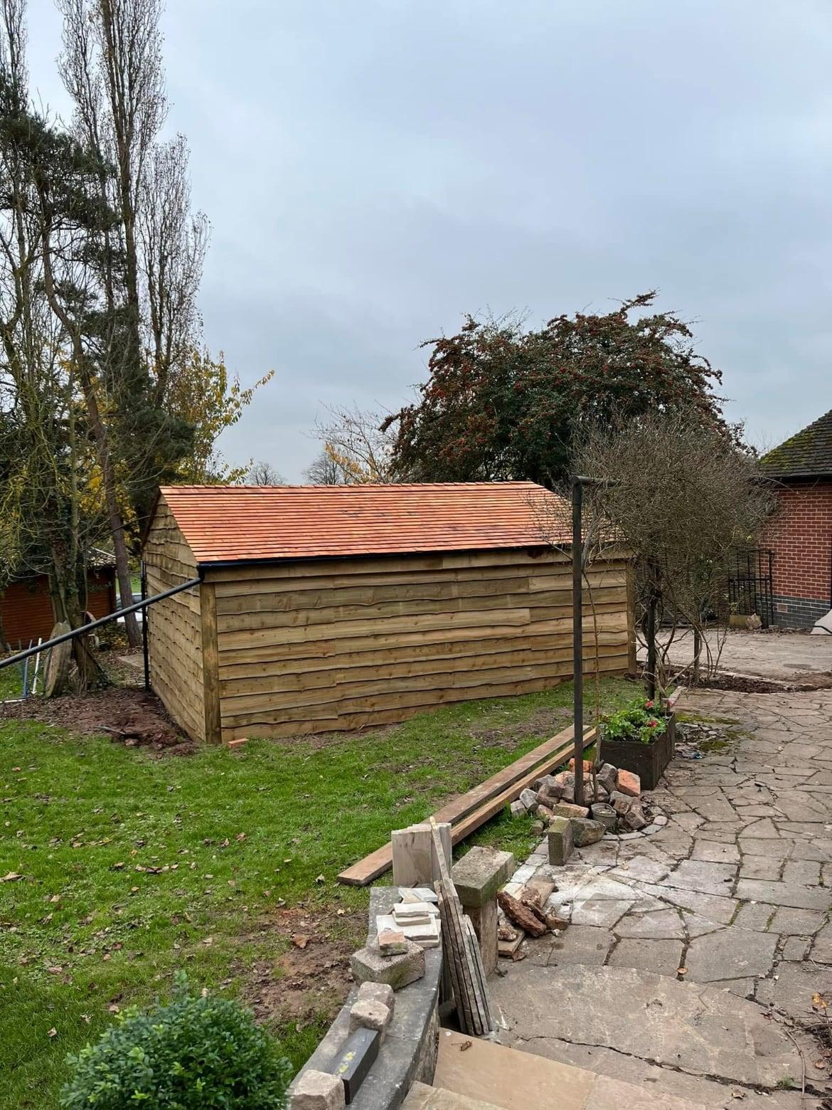 Timber outbuilding with a tiled roof in a large garden with crazy-paved steps