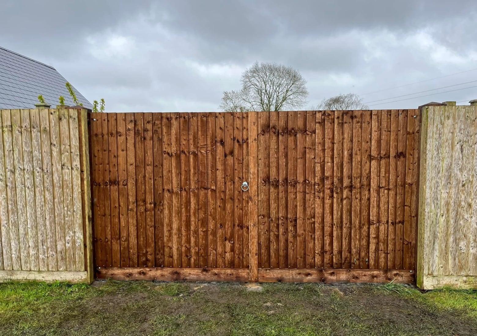 Pair of tall closeboard timber gates fitted between concrete fence posts